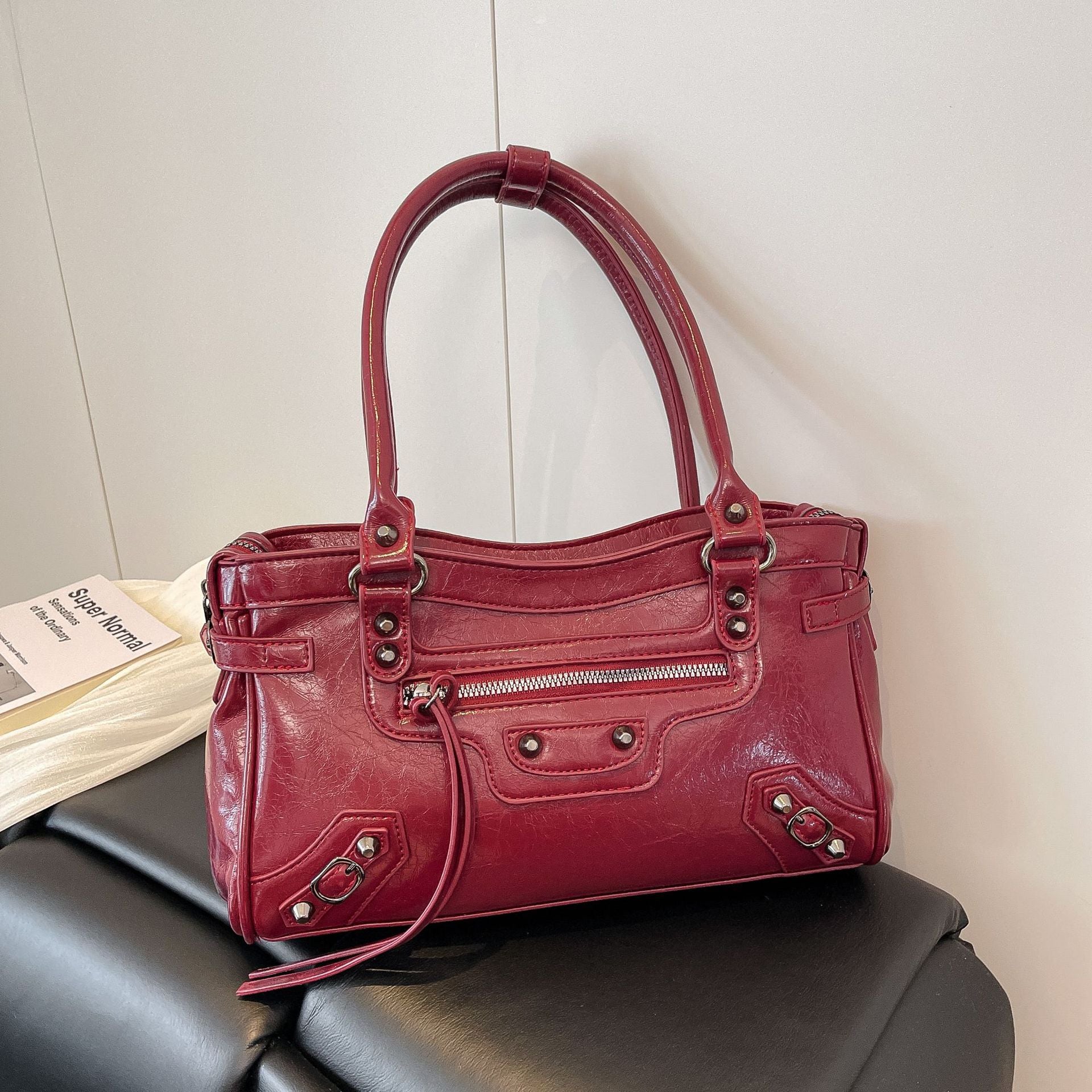 Red handbag on a black chair with a white wall background