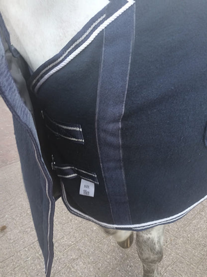Close-up of a horse saddle with a visible brand label on a concrete surface.
