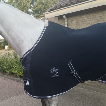 White horse wearing a black rug with a brand logo on a paved area.