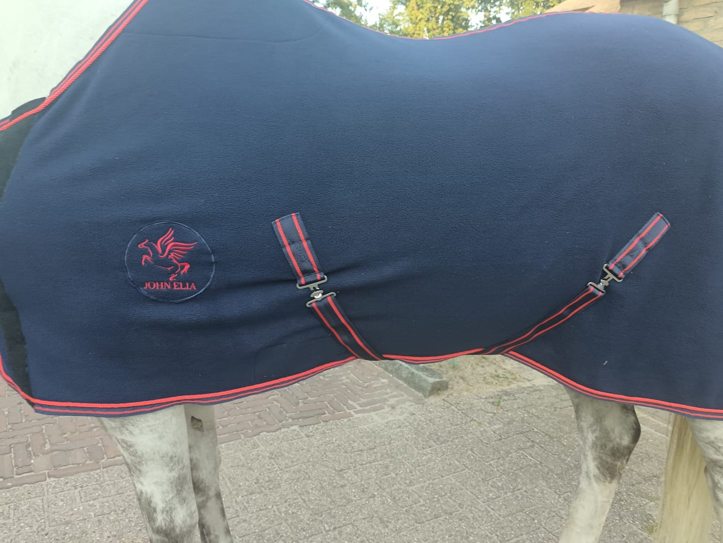 Navy blue horse blanket with red trim and a brand logo on a horse.